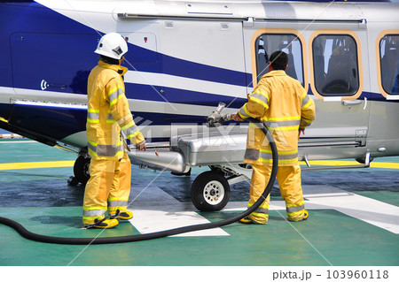 Helicopter Landing Officer communicating with pilot and copilot for service on ground and support as the pilot required. The helicopter landing on the deck and service by ground service team. Helicopter Landing Officer communicating with pilot and copilot for service on ground and support as the pilot required. The helicopter landing on the deck and service by ground service team. 103960118