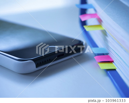 テーブルに置かれたスマートフォンと付箋の付いたファイル 103961333
