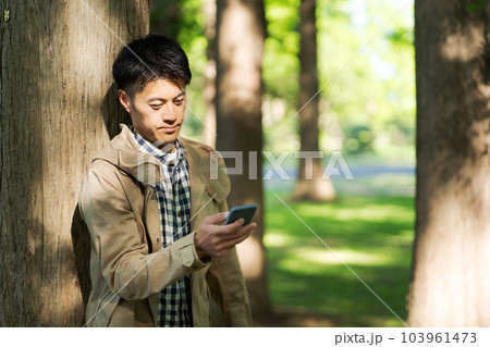 自然の中でスマホを持つ男性の写真 103961473