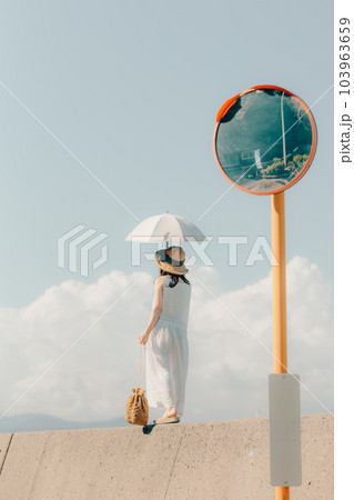 堤防に日傘をさして佇む女性 103963659