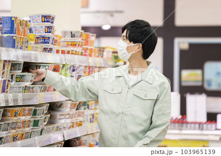 スーパーで買い物をする作業服姿の若い男性 103965139