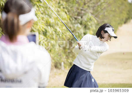 ゴルフプレイ中スマホで友達のスイングを撮影をするゴルフ女子 ゴルフプレイ中スマホで友達のスイングを撮影をするゴルフ女子 103965309