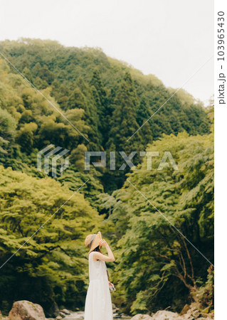 渓流でフィルムカメラを持って佇む女性 103965430