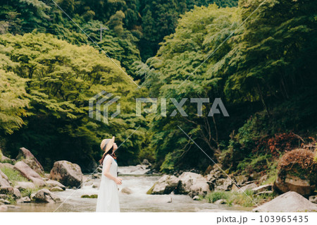渓流でフィルムカメラを持って佇む女性 103965435