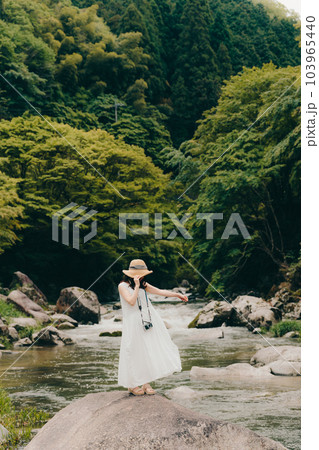 渓流でフィルムカメラを持って佇む女性 103965440