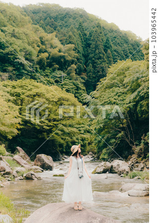 渓流でフィルムカメラを持って佇む女性 103965442