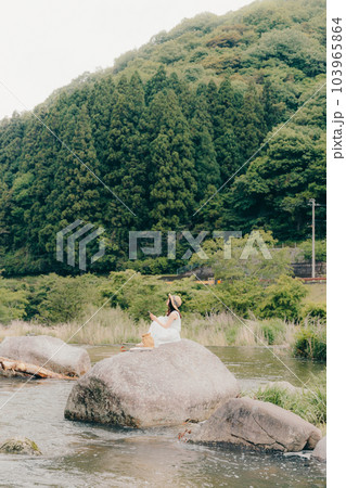 渓流でスマホを持って佇む女性 103965864