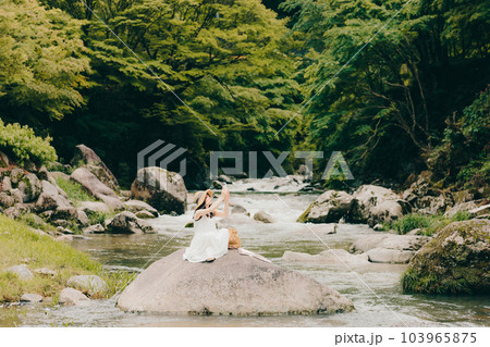渓流でスマホを持って佇む女性 103965875