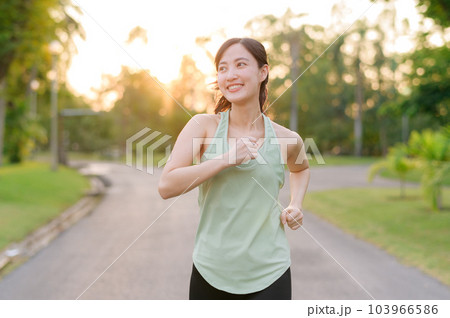 Fit Asian young woman jogging in park smiling happy running and enjoying a healthy outdoor lifestyle. Female jogger. Fitness runner girl in public park. healthy lifestyle and wellness being concept Fit Asian young woman jogging in park smiling happy running and enjoying a healthy outdoor lifestyle. Female jogger. Fitness runner girl in public park. healthy lifestyle and wellness being concept 103966586