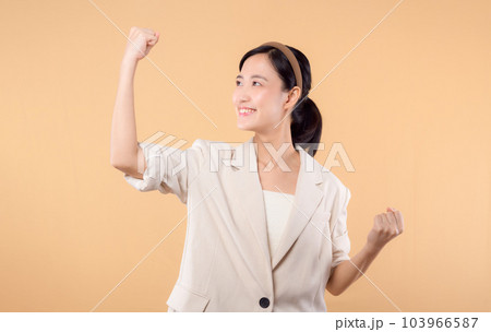 Studio portrait of happy successful confident young asian business woman. Beautiful young lady in white jacket smiling at camera standing isolated on solid beige colour copyspace background Studio portrait of happy successful confident young asian business woman. Beautiful young lady in white jacket smiling at camera standing isolated on solid beige colour copyspace background 103966587