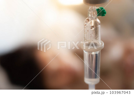 Set vitamin iv fluid intravenous drop saline drip with blur woman lying on bed in hospital room background. Medical Concept treatment emergency and injection drug infusion care chemotherapy concept. Set vitamin iv fluid intravenous drop saline drip with blur woman lying on bed in hospital room background. Medical Concept treatment emergency and injection drug infusion care chemotherapy concept. 103967043
