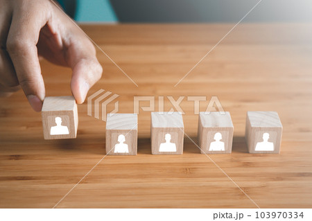 Businessman hold wooden block of staff icons. teamwork and organization concept Businessman hold wooden block of staff icons. teamwork and organization concept 103970334