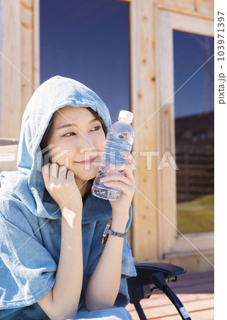 屋外サウナの前でサウナポンチョを着て外気浴をするサウナ女子 103971397
