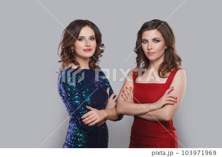 Perfect young adult women with makeup and brown curly hair posing against grey studio wall Perfect young adult women with makeup and brown curly hair posing against grey studio wall 103971969