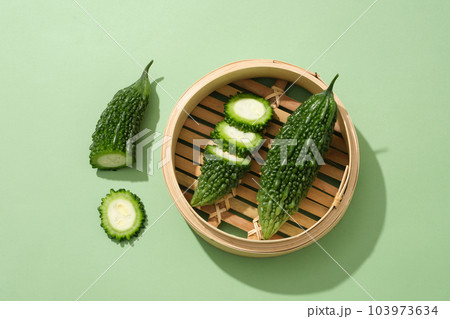 Bitter melon cut in slices placed inside a bamboo steam. Top view. Bitter melon (Momordica charantia) high in vitamins A and C and other nutrients 103973634