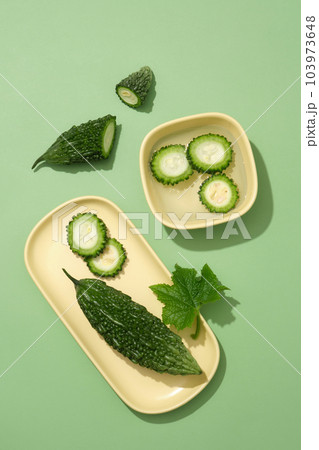 Yellow pastel bowl and dish filled with bitter melon slices and water. Bitter melon (Momordica charantia) is full of antioxidants, vitamins, and minerals 103973648