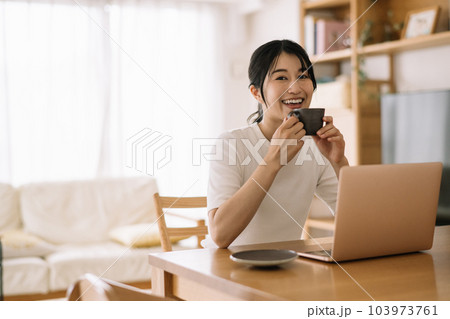 コーヒーを飲みながら在宅ワークをする女性 103973761
