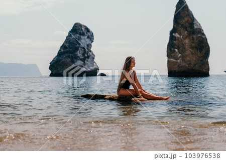 Woman summer travel sea. Happy tourist enjoy taking picture outdoors for memories. Woman traveler posing on the beach at sea surrounded by volcanic mountains, sharing travel adventure journey 103976538