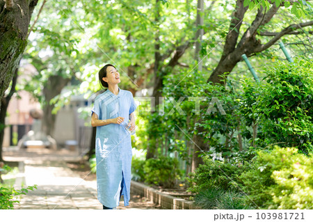 新緑の公園で水を飲む女性 103981721