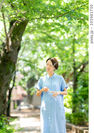 新緑の公園で水を飲む女性 103981730