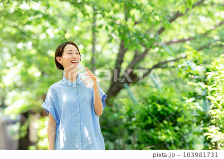 新緑の公園で水を飲む女性 103981731