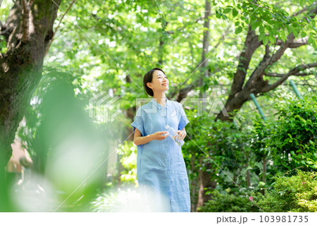新緑の公園で水を飲む女性 103981735