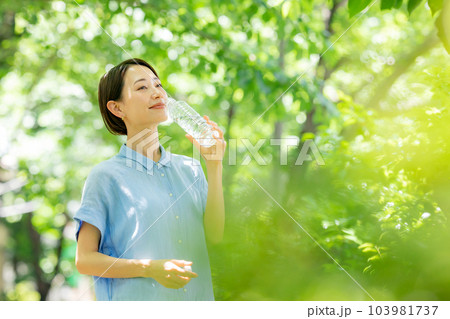 新緑の公園で水を飲む女性 103981737