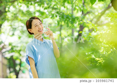 新緑の公園で水を飲む女性 103981741