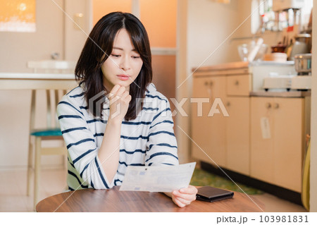 電気料金の高騰で頭を抱える若い女性 103981831