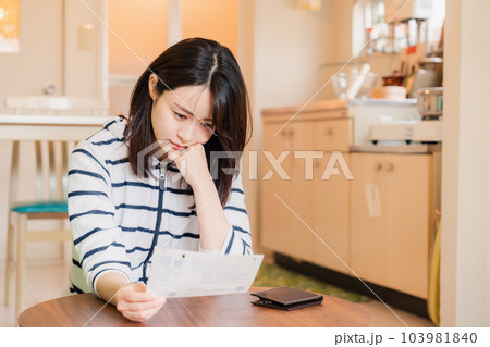 電気料金の高騰で頭を抱える若い女性 103981840