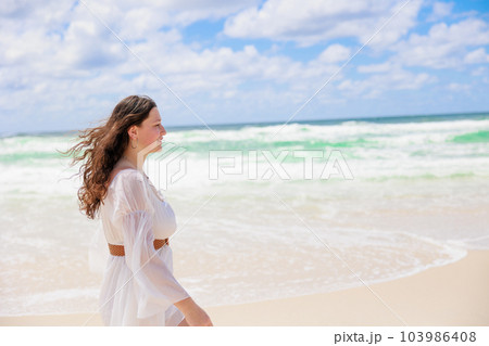 海辺を歩く白いドレスの白人の少女の横顔 103986408