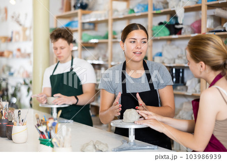 Potter teaches teenagers how to make pottery out of clay in workshop 103986939