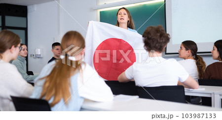 Female professor shows students flag of Japan Female professor shows students flag of Japan 103987133