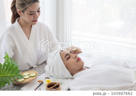 Relaxed young asian woman getting eye nature treatment by cucumber at spa salon. Wellness and healing concept. Relaxed young asian woman getting eye nature treatment by cucumber at spa salon. Wellness and healing concept. 103987662