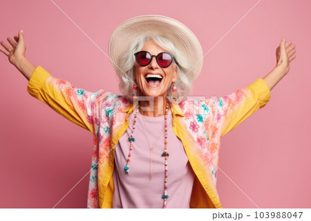 Cheerful lady with stylish accessories spreading hands to sides laughing grey-haired joyful woman in sunglasses and hat feeling happy standing on pink background .generative AI 103988047
