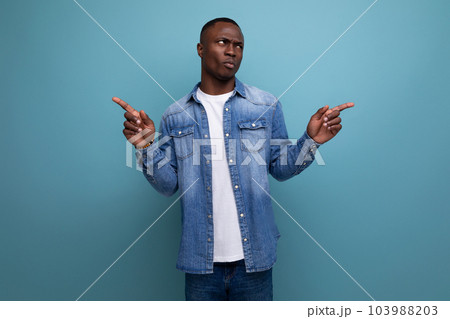 young handsome african guy in spring urban clothes pointing with his hands to the side on isolated young handsome african guy in spring urban clothes pointing with his hands to the side on isolated 103988203