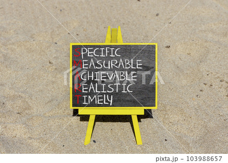 SMART symbol. Concept words SMART specific measurable achievable realistic timely on blackboard. Beautiful sand background. Business SMART specific measurable achievable realistic timely concept. 103988657