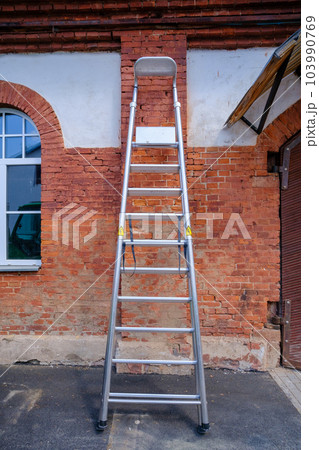Aluminum stairs bent next to the wall of the house Aluminum stairs bent next to the wall of the house 103990769