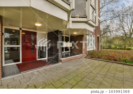 a red door in front of a brick building with green grass and flowers on the ground next to the entrance a red door in front of a brick building with green grass and flowers on the ground next to the entrance 103991369