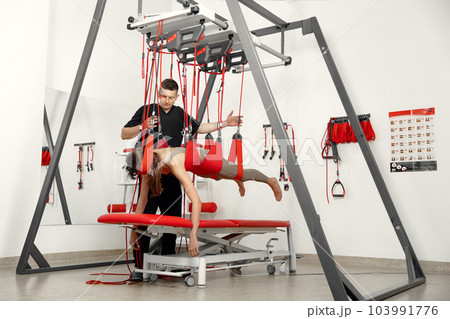 physical therapy, Physical rehabilitation, Health-improving exercises, doing exercises, decompression simulators. Rehabilitation exercises on red cord slings to restore pain-free movement patterns and 103991776