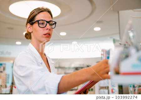 Woman working in the pharmacy looks for the medicine 103992274