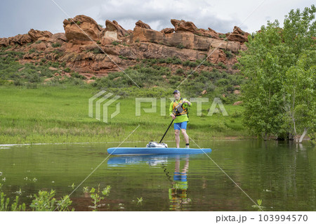 senior male paddler on a touring stand up paddleboard on lake in Colorado foothills - Horsetooth Reservoir near Fort Collins 103994570