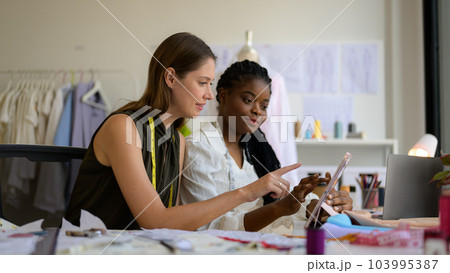 Happy female dressmaker working in workshop studio Happy female dressmaker working in workshop studio 103995387