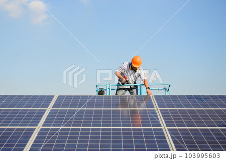 Professional technician worker installing solar panels at solar cell farm Professional technician worker installing solar panels at solar cell farm 103995603