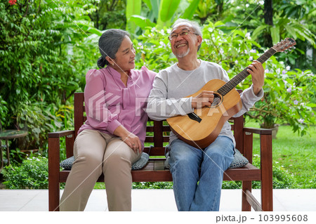Happy senior grandparents playing guitar and singing songs having fun 103995608