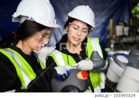 Couple of happy female maintenance engineers working at factory 103995824
