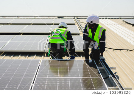 Engineers with safety helmet checking solar system at solar power farm 103995826