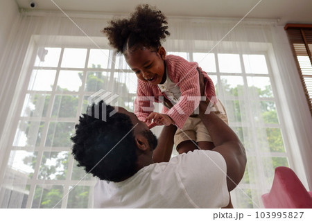 Happy daughter playing with father at home 103995827