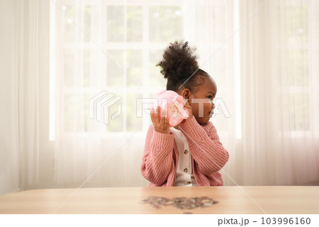 Little girl putting coin of cash into ceramic piggy bank Little girl putting coin of cash into ceramic piggy bank 103996160