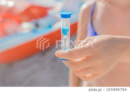 The girl's hand holds a close-up hourglass. The concept of leaky time The girl's hand holds a close-up hourglass. The concept of leaky time 103996784